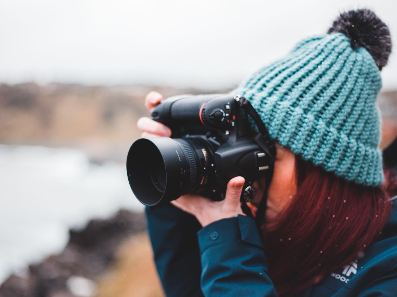 Photographer using a professional DSLR camera outdoors, demonstrating that skill matters as much as gear.